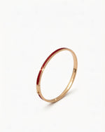 Elegant 14K gold bangle with flowing burgundy enamel, designed for luck and energy on the wrist