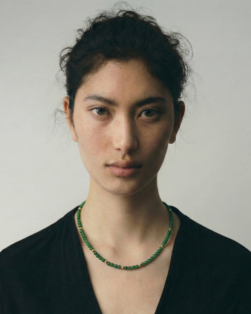 Close detail of green jade beads with gold details on a necklace