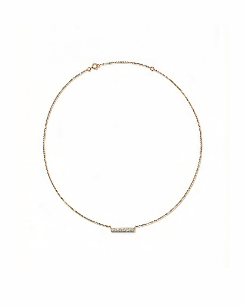 Gold diamond bar necklace layered with a fine gold chain, worn at the collarbone