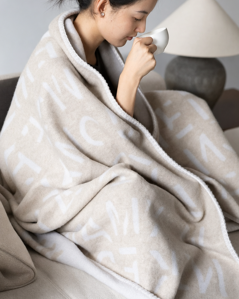 Woman wrapped in oat cashmere blanket sipping from cup