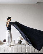 Woman throwing grey cashmere blanket over sofa