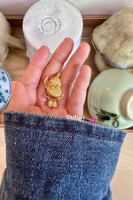 Model holding Golden Parrot brooch, showcasing luxury styling